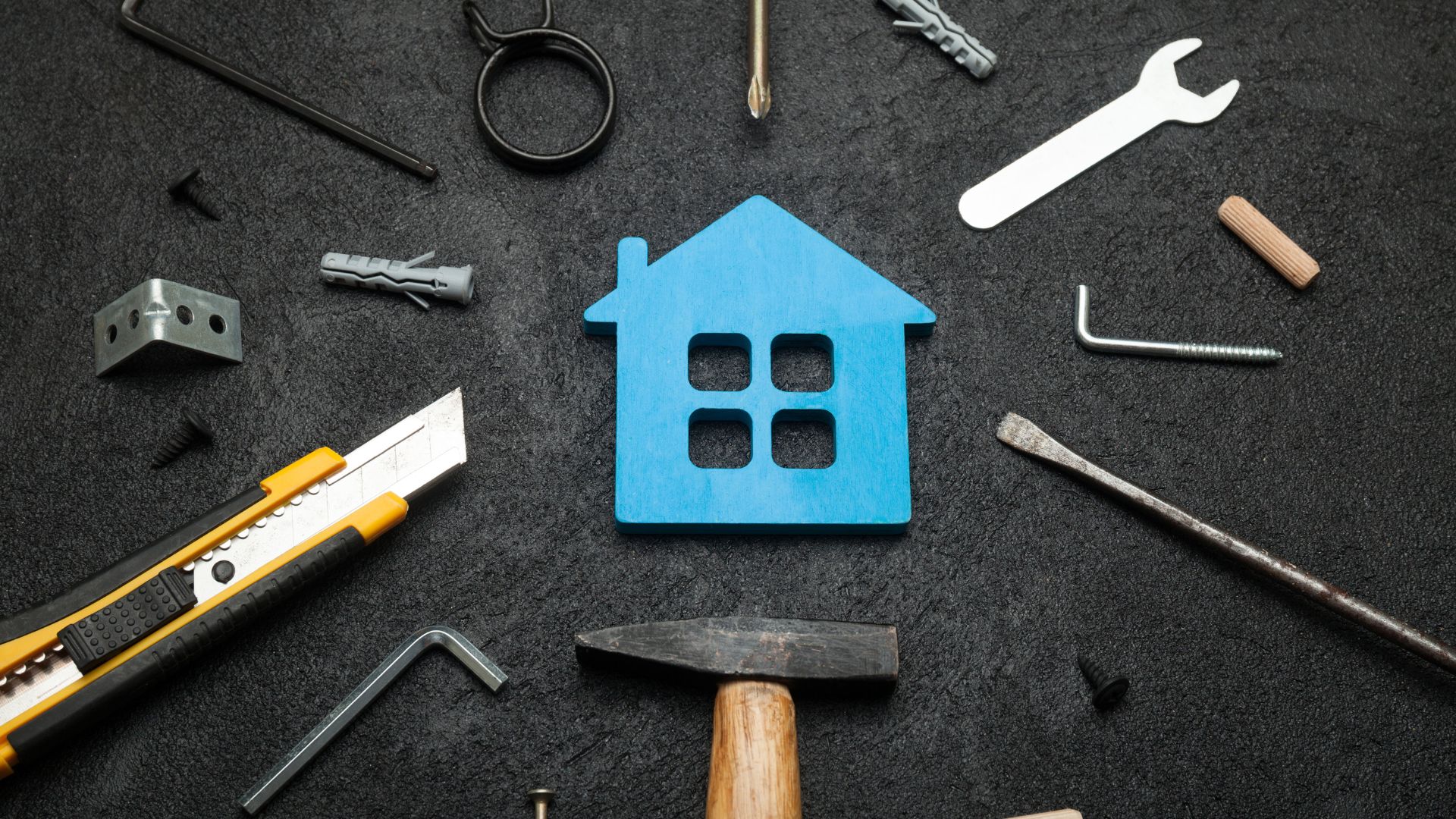 Blue house icon surrounded by various tools on dark background